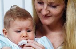 Mother wiping her baby’s gums with a wet cloth